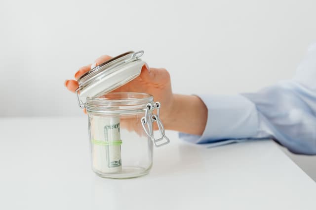 Pièces de monnaie déposées dans un bocal en verre, symbole d'épargne