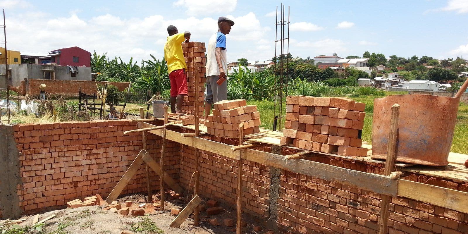 Deux maçons montant un mur de briques sur un chantier à Antananarivo
