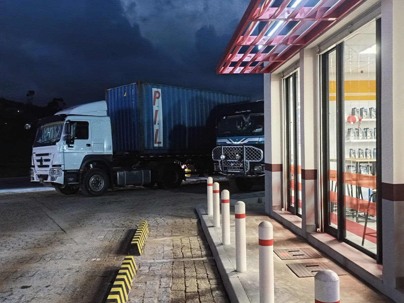 Station-service de nuit à Manjakandriana, avec deux camions sur la piste