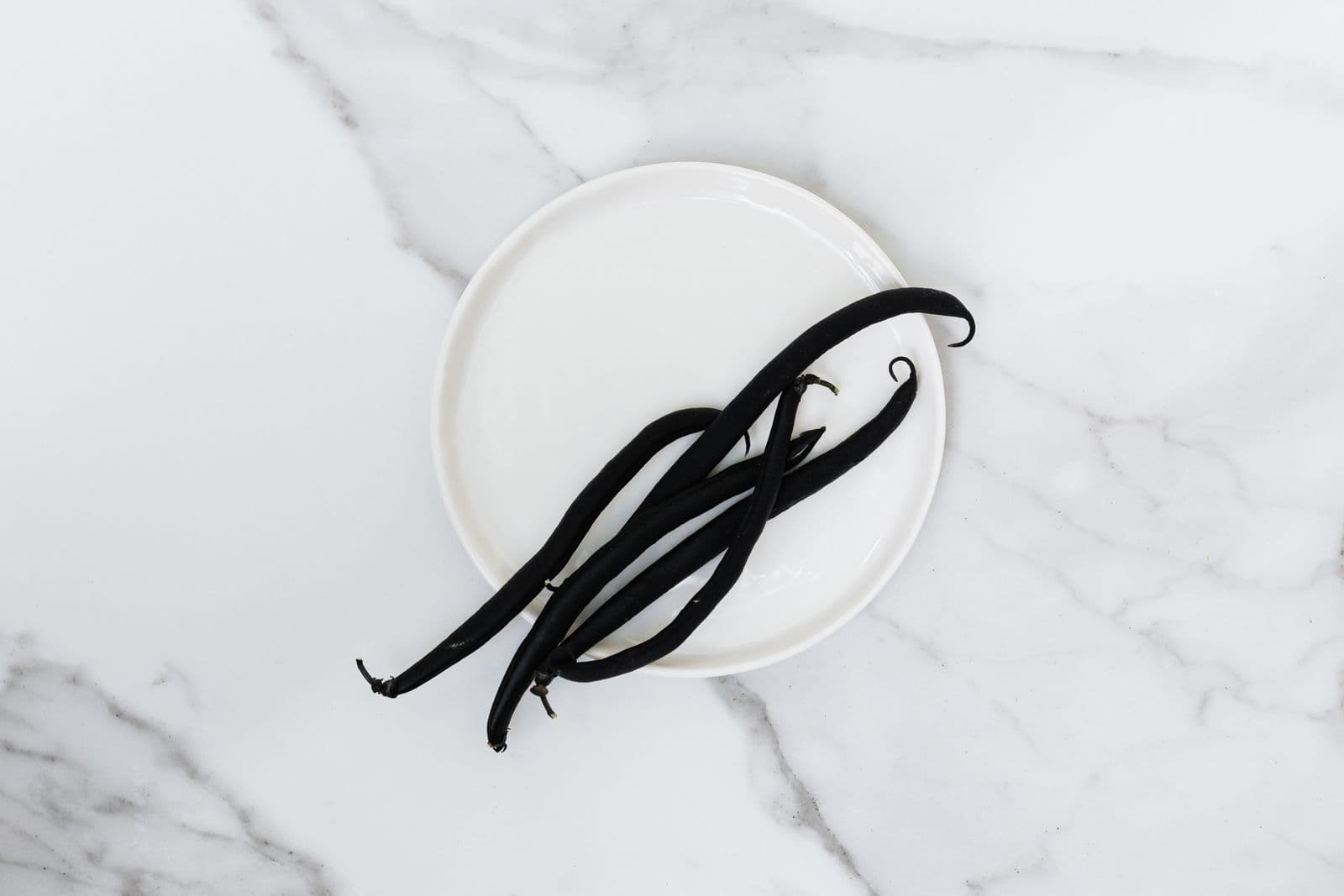 Gousses de vanille noires sur une assiette blanche