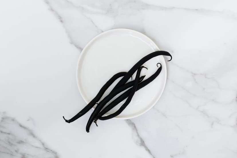 Gousses de vanille noires sur une assiette blanche